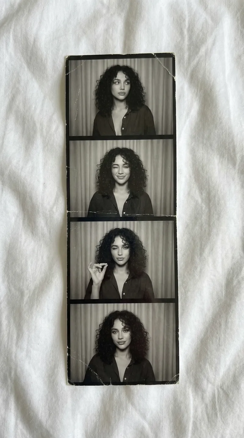 A vertical black-and-white photostrip lies softly atop white…